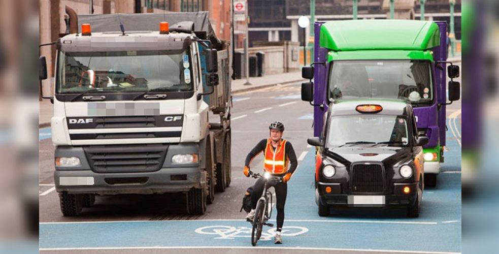 cyclist, taxi and lorries waiting at traffic lights
