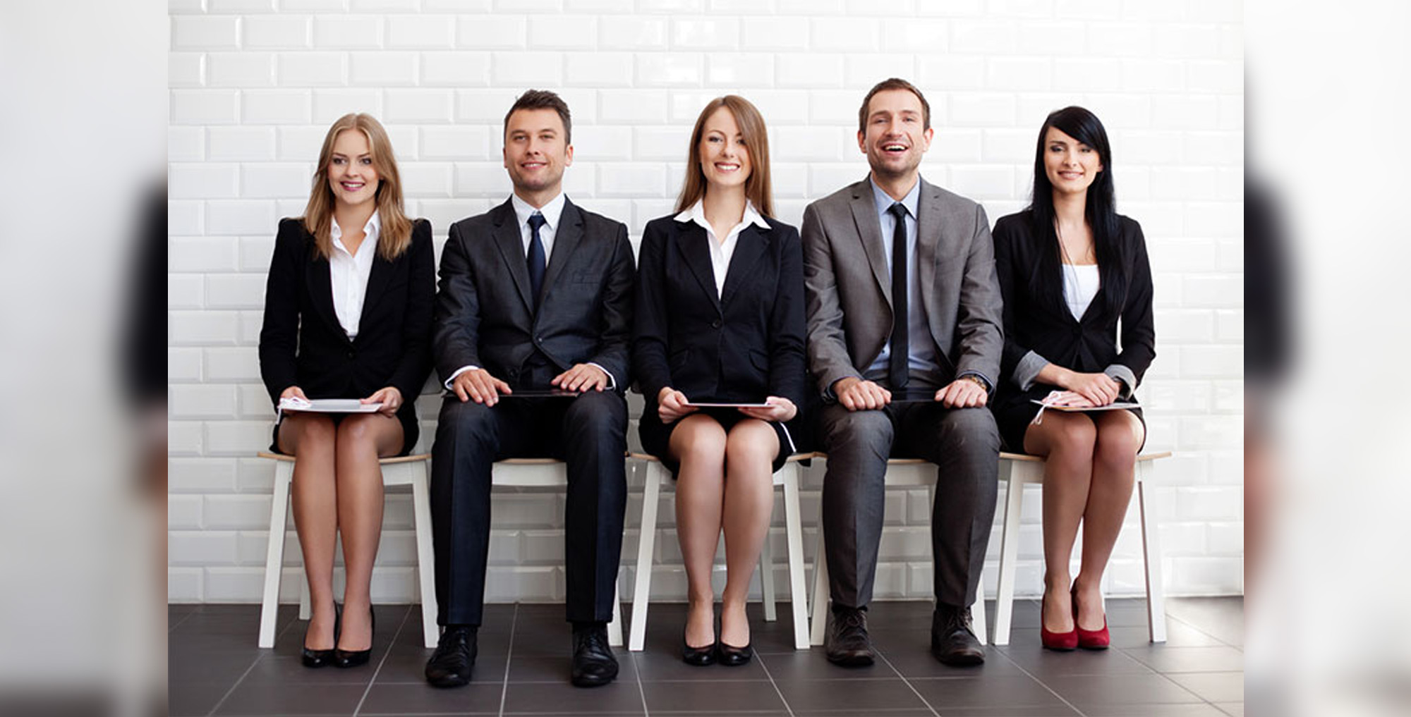 candidates sat in a line infornt of white brick wall