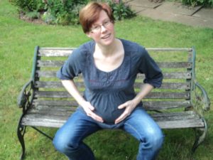 Lucy Yorke with pregnancy bump sat on a bench